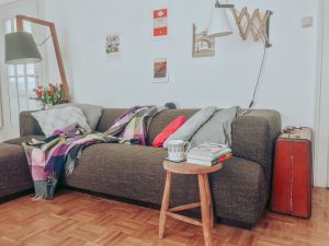 Monas Couch mit Holztischen, Teetasse und Büchern - der Inbegriff von Gemütlichkeit